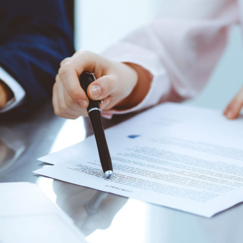 Group of business people and lawyers discussing contract papers sitting at the table, close up